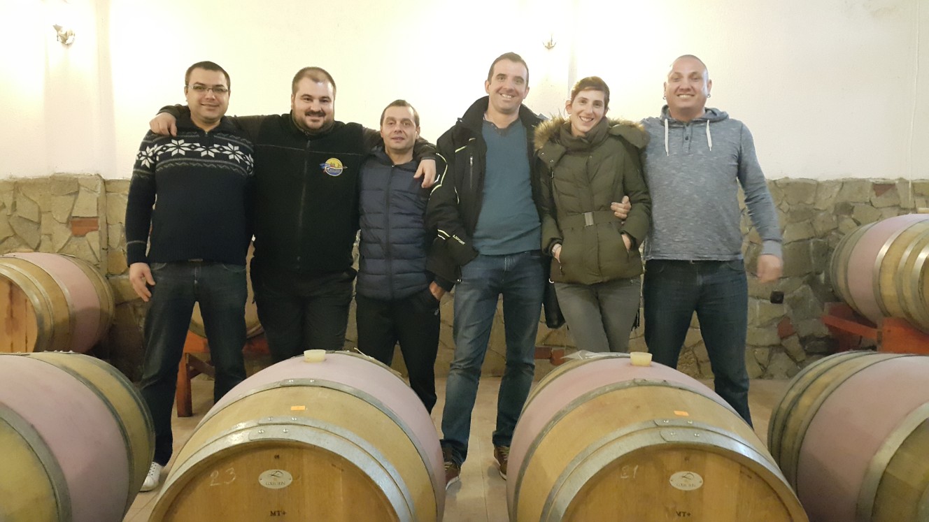 Щастлива група посетители на винарска изба "Кьосев" пред бъчви